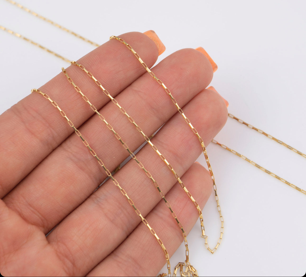 Feine Gliederarmbänder aus 18k Gelbgold auf einer Hand drapiert – 19 cm Länge.