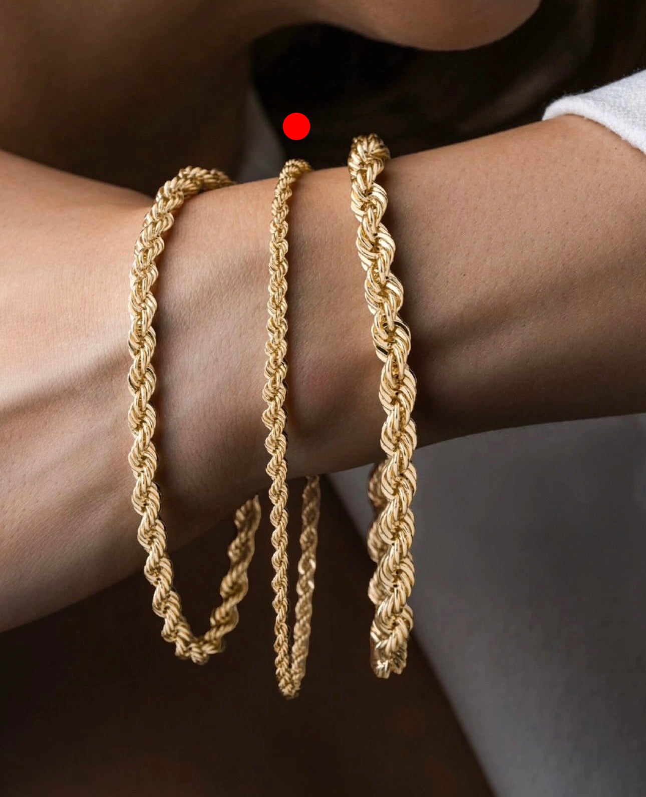 Nahaufnahme eines eleganten Armbands aus 18k Gelbgold – Tanab-e Tala (Goldene Kordel) – mit kunstvoll gedrehter Kordelstruktur, das stilvoll um das Handgelenk einer Person gelegt ist.