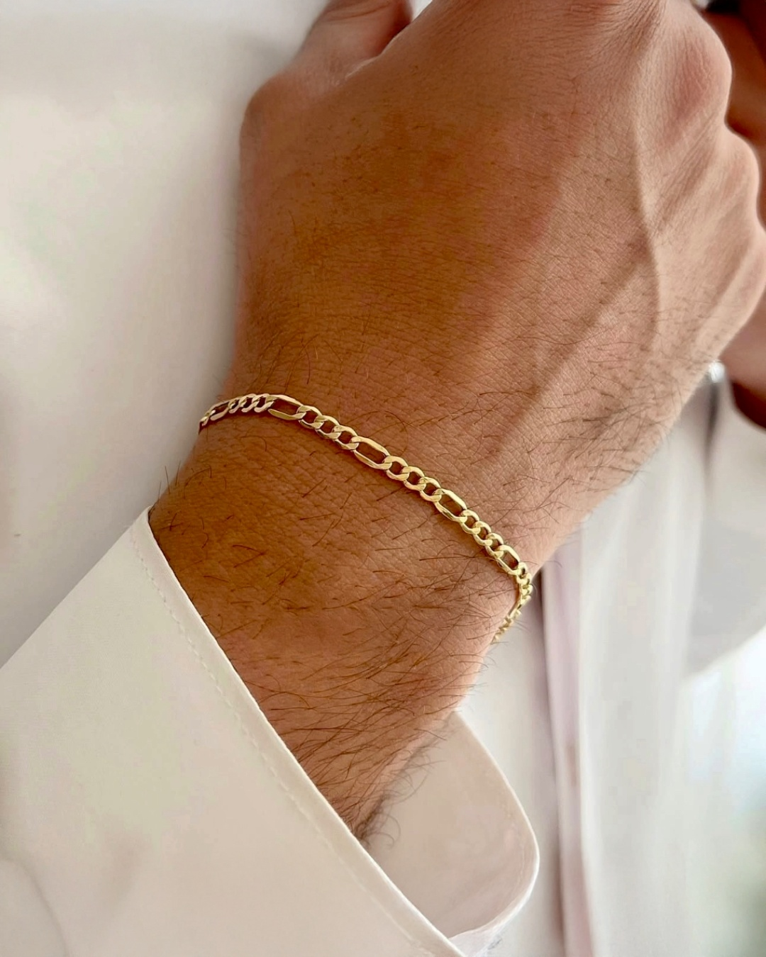 18 Karat Gelbgold-Figaro-Armband am Handgelenk getragen – eleganter, zeitloser Goldschmuck aus massivem 18k Gold, hochwertig verarbeitet und stilvoll kombiniert.