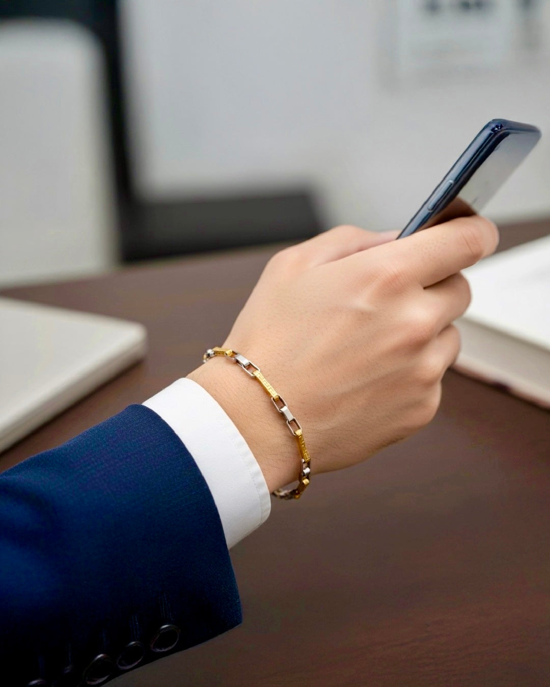 Elegantes 18k Goldarmband in Gelbgold und Weissgold am Handgelenk, getragen zu Anzug und Smartphone – zeitloser Luxus im Alltag.