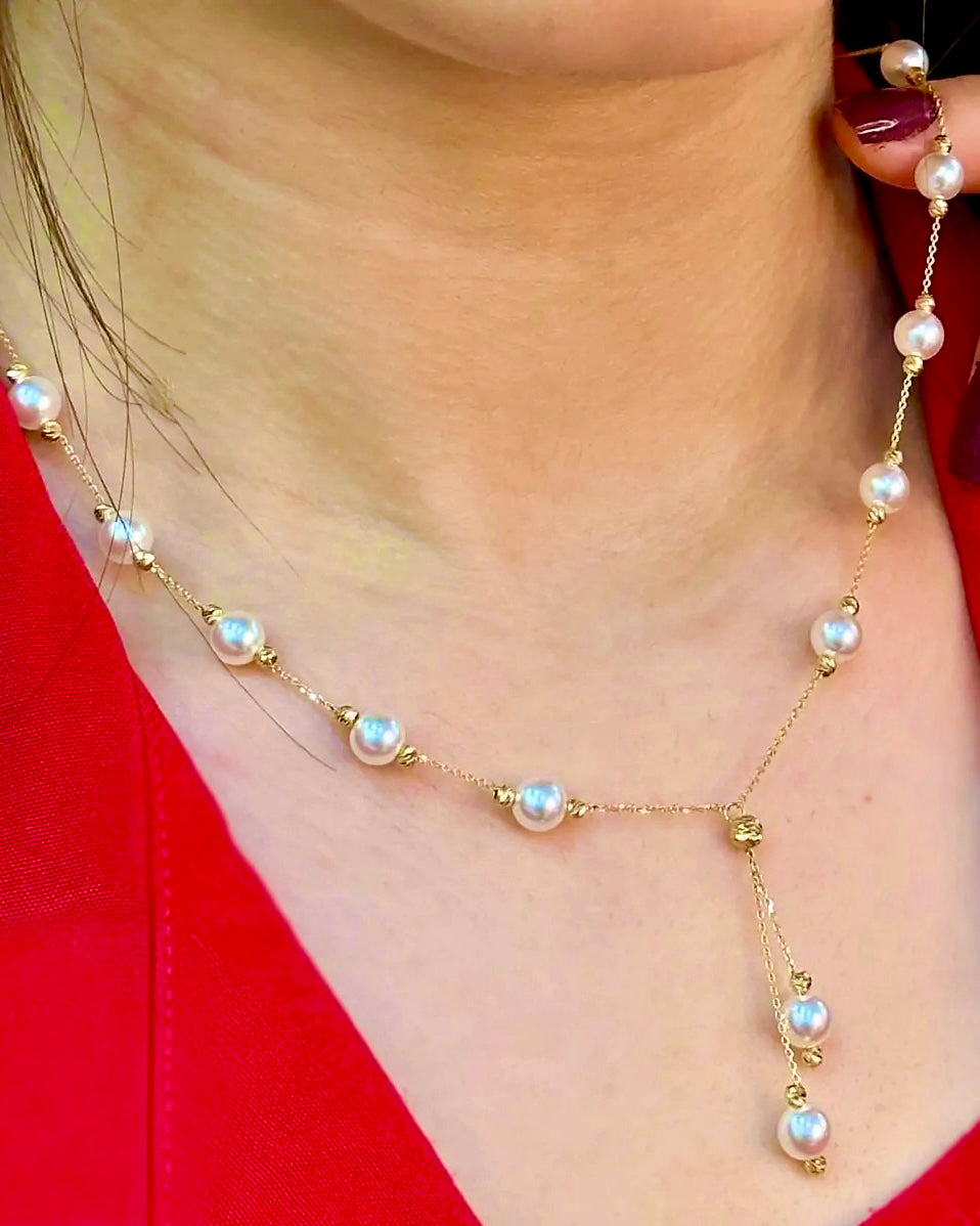 Halskette „Morvarid-e Sefid Raghsan“ aus 18 Karat Gelbgold – feine Kette mit weißen Perlen, die elegant verteilt und im unteren Teil tanzend herabhängen, getragen am Hals über einem roten Outfit.