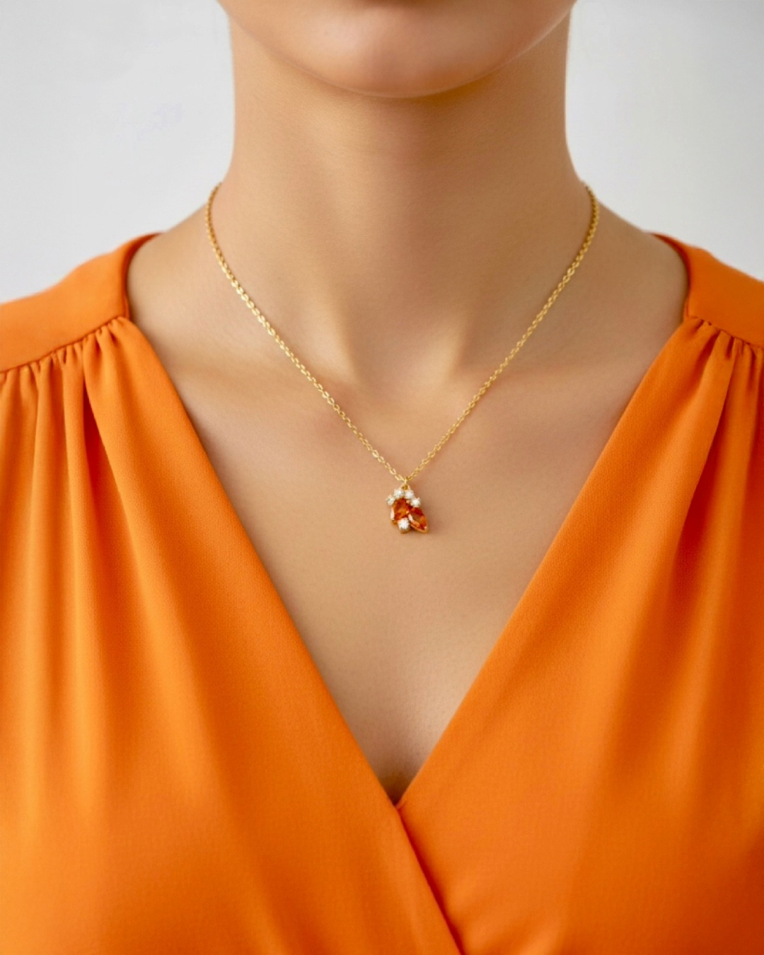 18k Gelbgold Halskette mit filigranem Anhänger aus orangefarbenem Edelstein und kleinen Diamanten, elegant getragen am Hals, feiner Goldschmuck in luxuriöser Ausstrahlung.