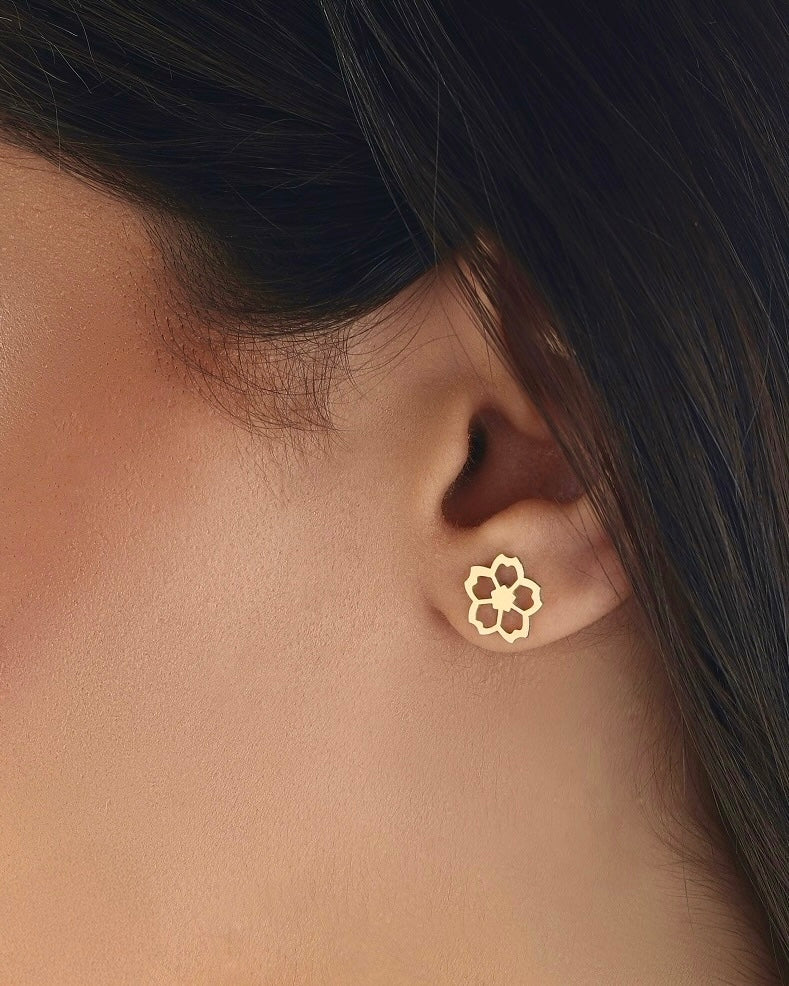 Nahaufnahme eines Ohres mit einem filigranen Ohrstecker aus 18 Karat Gelbgold – Design in Form einer zarten Blüte mit offenen Linien, elegant und minimalistisch getragen.