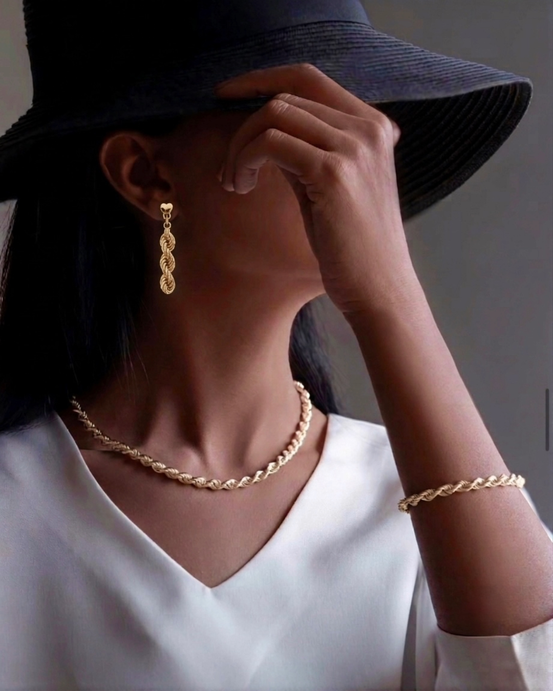 Frau trägt 18k Gelbgold Ohrstecker Tanab-e Tala mit geflochtener Gliederstruktur sowie passende Halskette und Armband