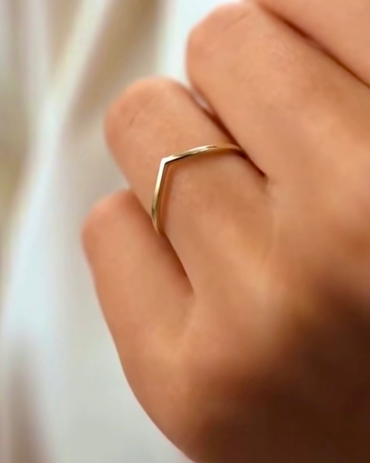 Nahaufnahme einer Hand mit dem Ring „Khatt-e Del“ aus 18 Karat Gelbgold – schlichtes, minimalistisches Design in Form einer feinen V-Linie, symbolisch als „Linie des Herzens“, elegant am Finger getragen.