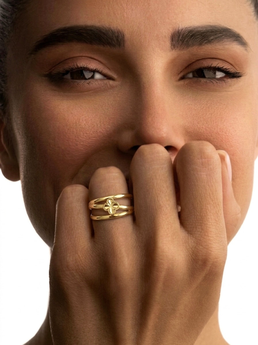 Eleganter Kleeblatt-Ring aus 18 Karat Gelbgold am Finger einer Frau getragen. Hochglanzpoliertes Design mit filigranem vierblättrigem Kleeblatt als Symbol für Glück, Stil und zeitlose Eleganz.