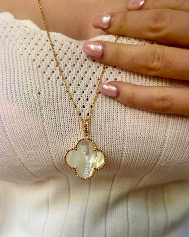 18k Gelbgold-Halskette mit kleeblattförmigem Anhänger aus schimmerndem Perlmutt, filigrane Goldfassung, getragen am Dekolleté, elegante Damenkette in Nahaufnahme.