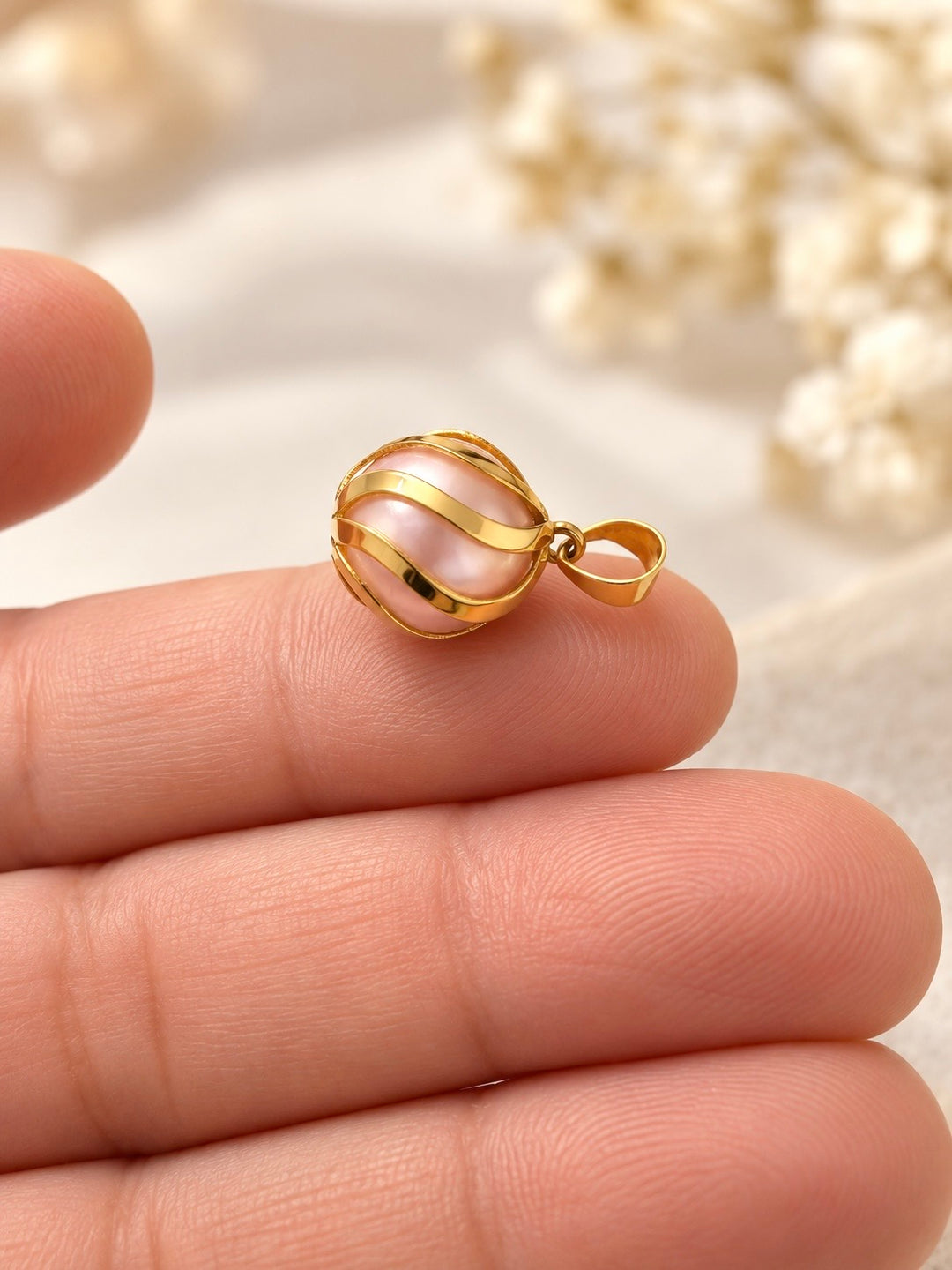 Seitliche Nahaufnahme des Shokoufeh Goldanhängers mit zartrosa Kunstperle, spiralförmigen Goldbändern und Anhängeröse.