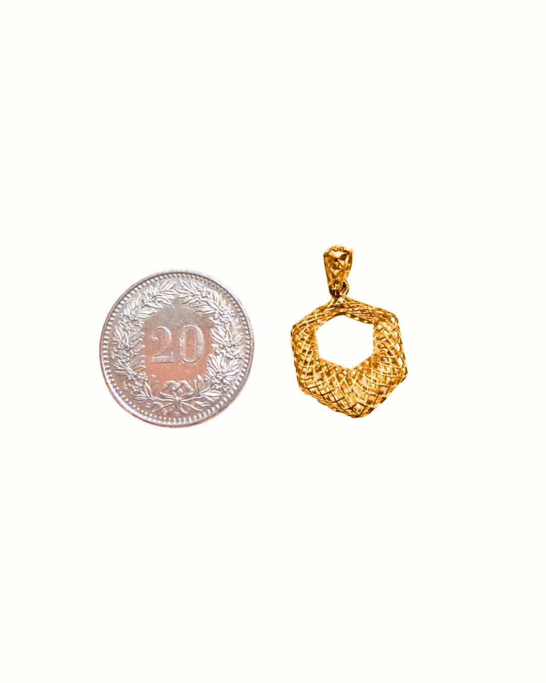 Anhänger aus 18k Gelbgold im Sechseck-Design neben einer 20-Rappen-Münze – Grössenvergleich des Modells Shesh Goshah-ye Mushabbak (Sechseck aus Spitze). Zeigt reale Proportionen des Schmuckstücks.