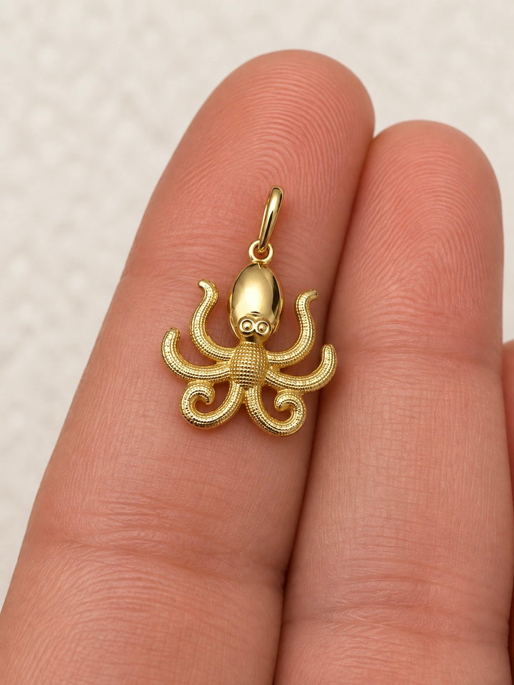 Anhänger aus 18k Gelbgold in Form eines detailreich gestalteten Oktopus mit geschwungenen Tentakeln und feiner Oberflächenstruktur, auf einer Hand präsentiert.