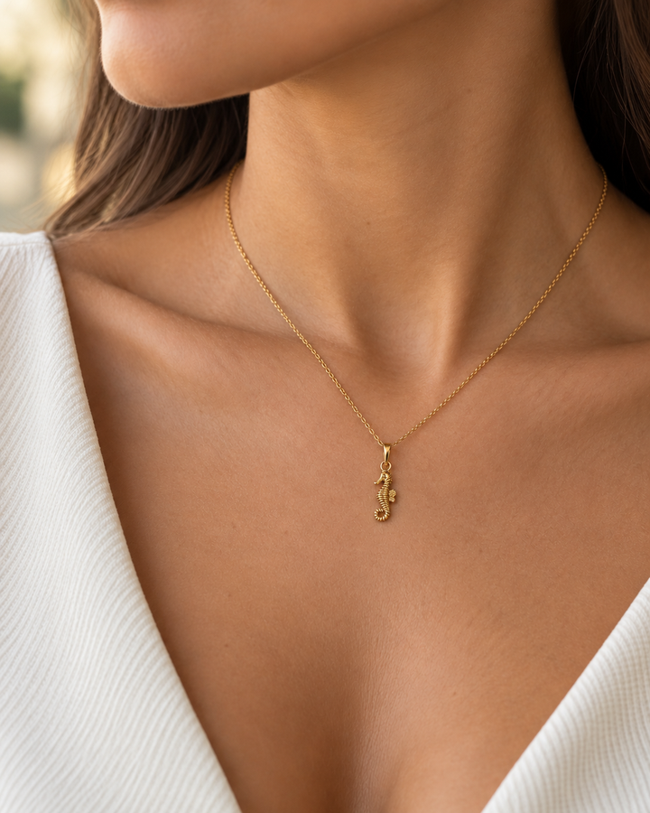 Frau trägt den filigranen Asb-e Daryayi Seepferdchen-Anhänger aus 18k Gelbgold an einer feinen Goldkette