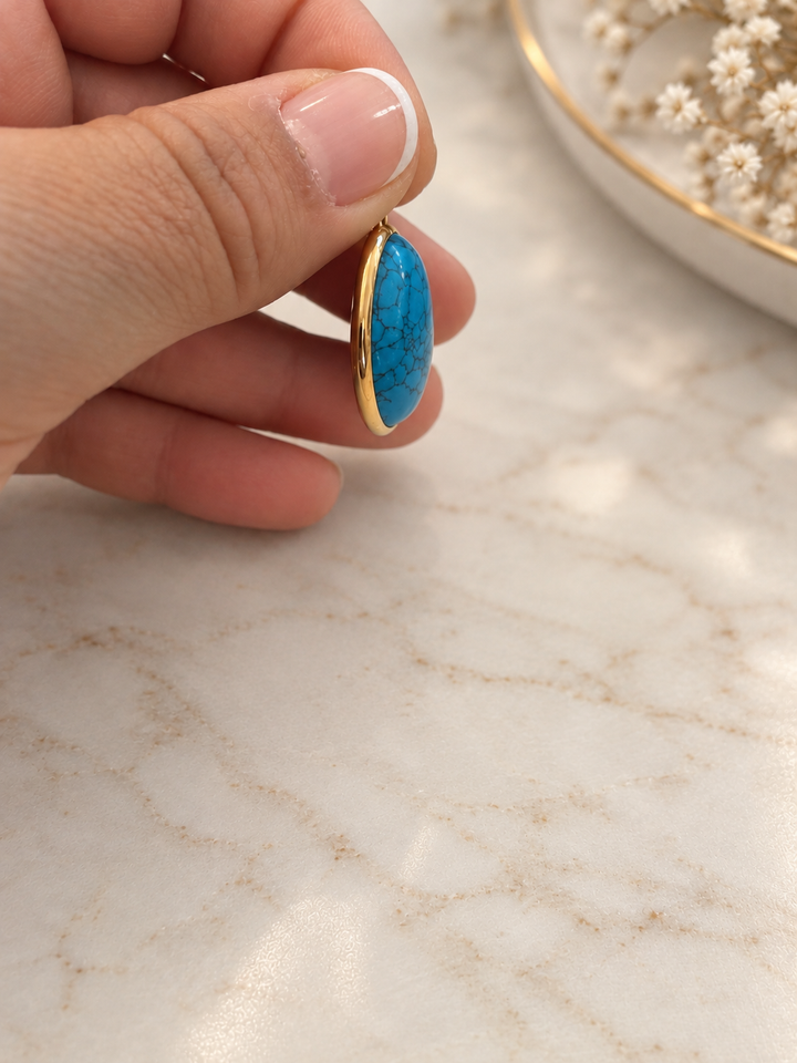 Seitenansicht des Aseman Anhängers mit gewölbtem blauem Schmuckstein und Einfassung aus 18k Gelbgold