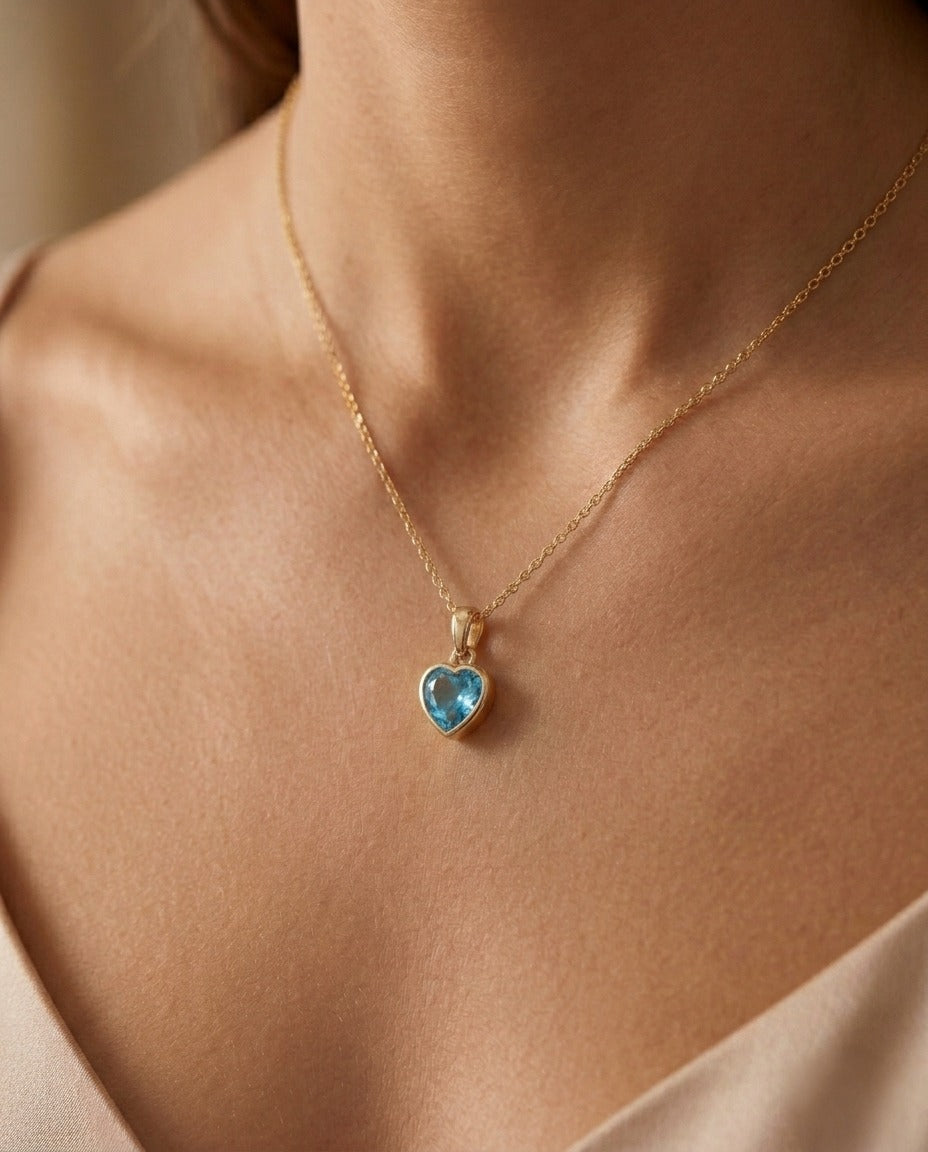 Herzanhänger aus 18k Gelbgold mit himmelblauer Zirkonia, getragen an einer feinen Goldkette.