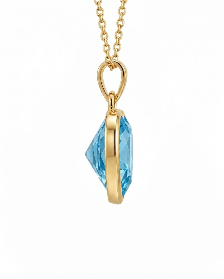 Seitenansicht eines Herzanhängers aus 18k Gelbgold mit facettierter himmelblauer Zirkonia.
