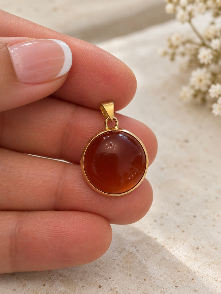    Nahaufnahme des runden cognac-roten Schmucksteins mit Goldfassung