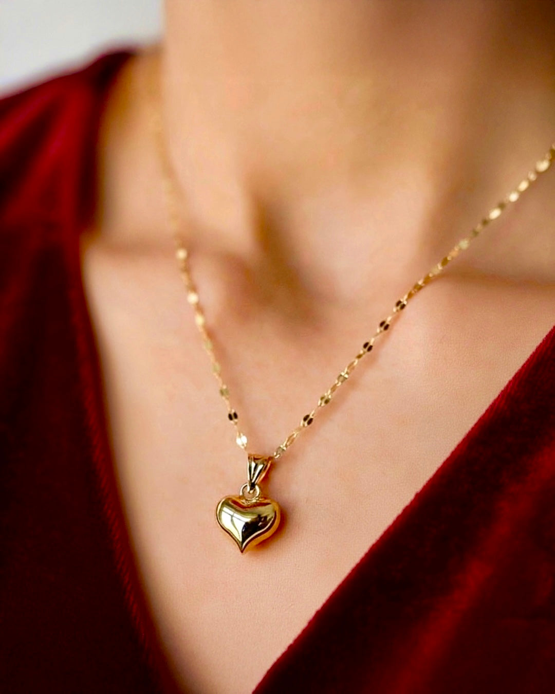 Nahaufnahme eines eleganten 18k-Gelbgold-Herzanhängers an feiner Goldkette, getragen am Dekolleté, warmes Licht, hochwertige und emotionale Schmuckfotografie.