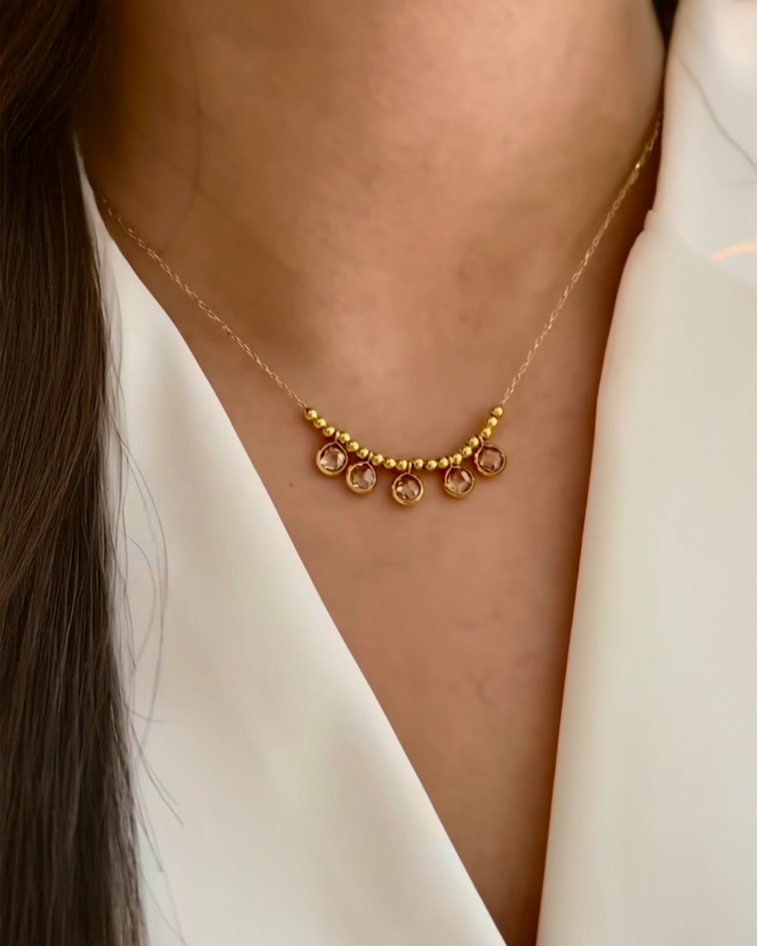18k Gold Halskette mit fünf kleinen runden Anhängern und goldenen Kugeln, elegant getragen am Hals einer Frau.