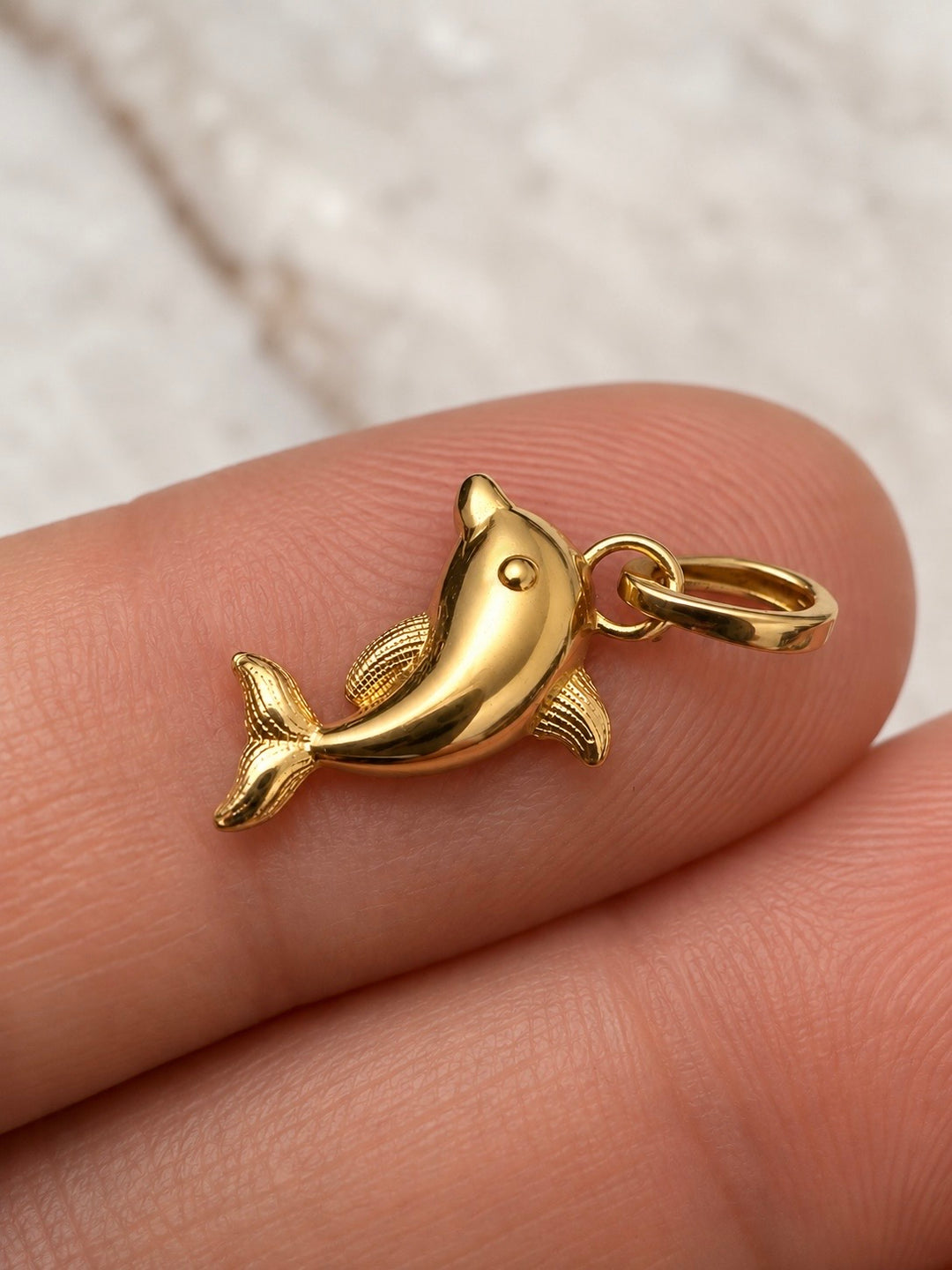Detailansicht des Dolfin-e Bazigush Delfin-Anhängers aus 18k Gelbgold auf der Hand