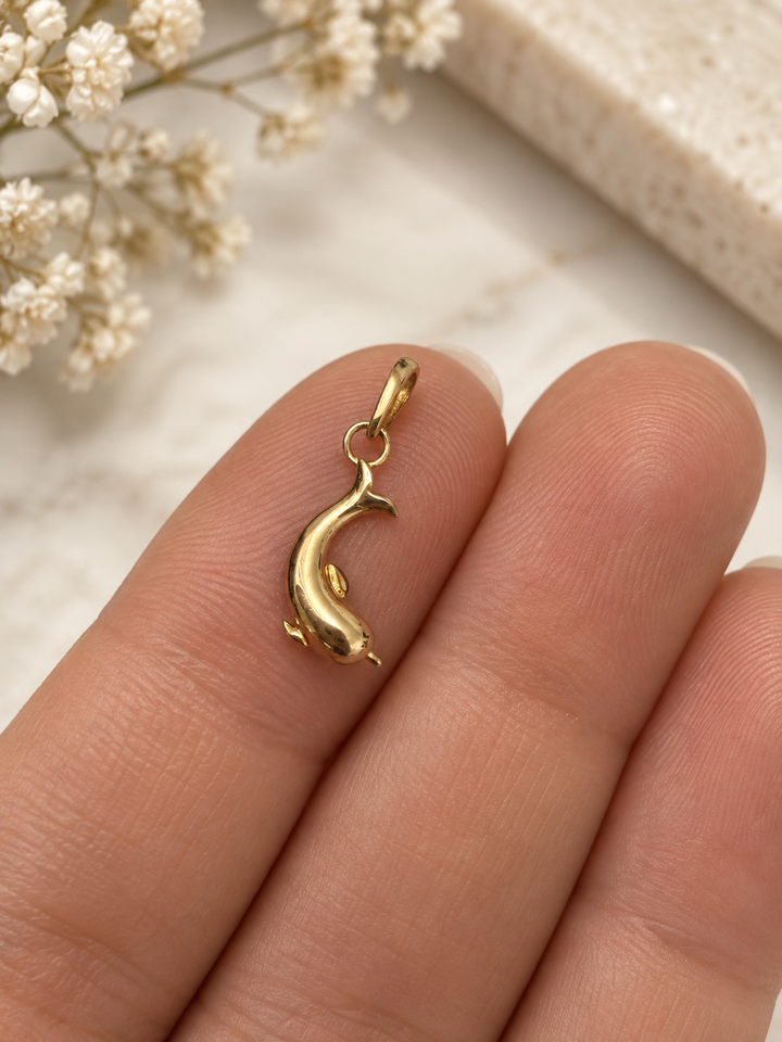 Kleiner goldener Delfin-Anhänger Dolfin-e Tala aus 18k Gelbgold auf der Hand