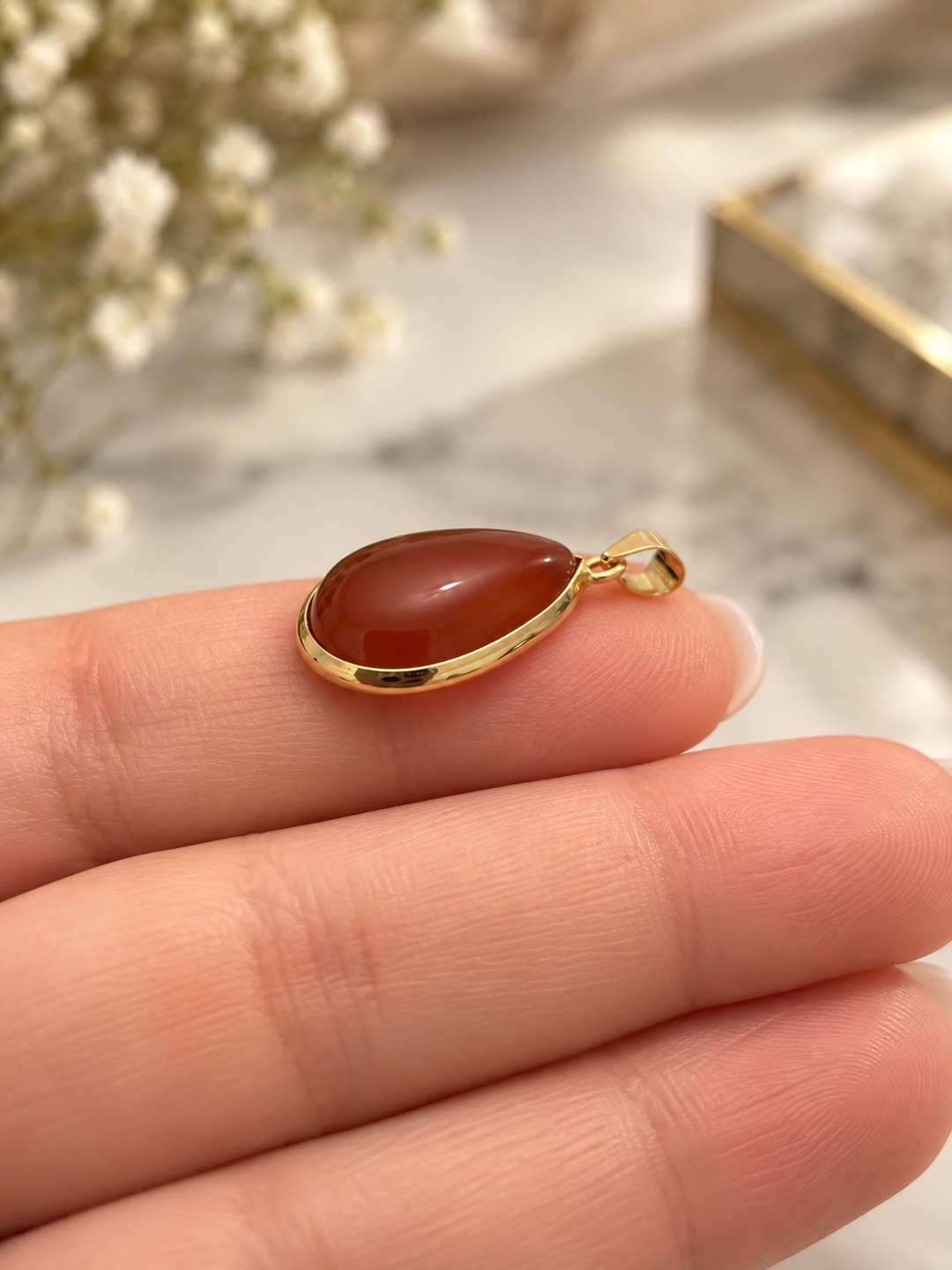 Seitenansicht eines roten Tropfenanhängers aus 18k Gelbgold mit gewölbtem synthetischem Schmuckstein und polierter Goldfassung.