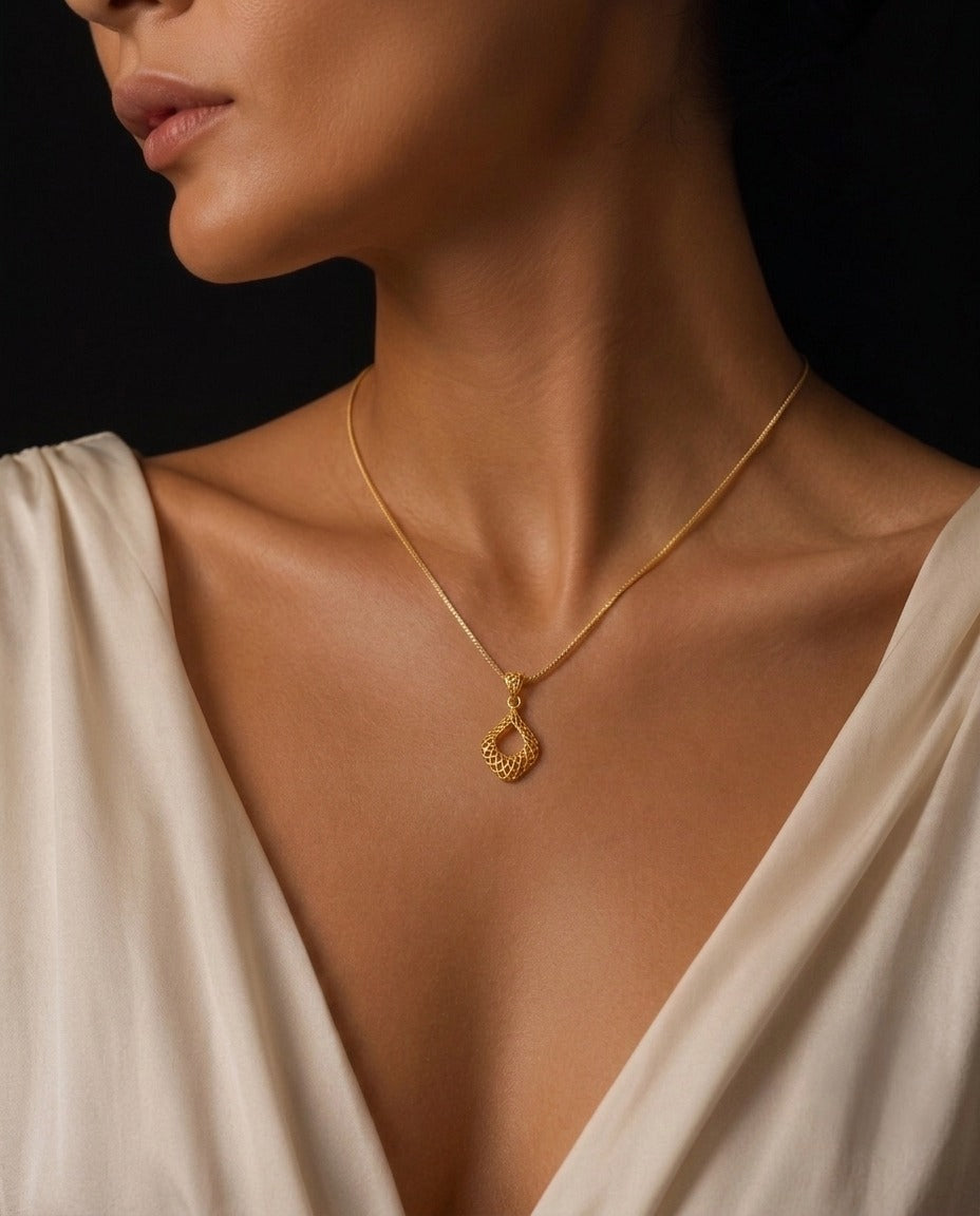 Elegante 18 Karat Gelbgold-Halskette mit filigranem tropfenförmigem Anhänger in persischem Design, getragen von einem weiblichen Model. Der handgefertigte Goldanhänger mit feiner Struktur wird stilvoll auf einem cremefarbenen Kleid präsentiert und unterstreicht zeitlose Eleganz sowie luxuriösen Schmuck für Damen.