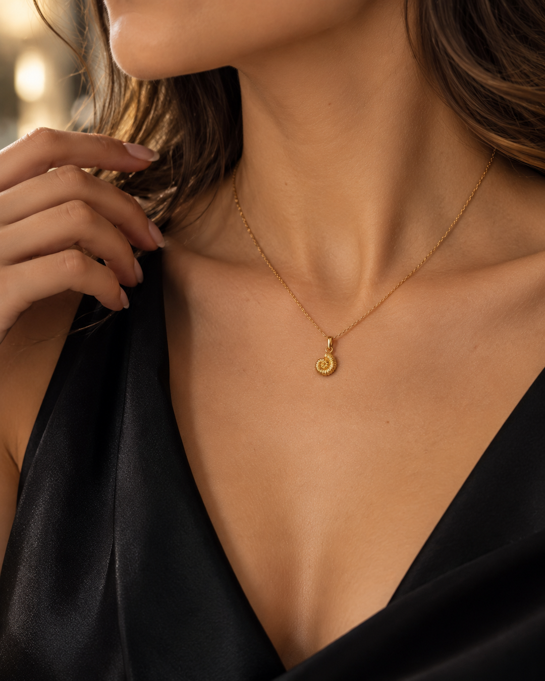 Frau trägt den Halazoon Schneckenhaus-Anhänger aus 18k Gelbgold an einer feinen Goldkette
