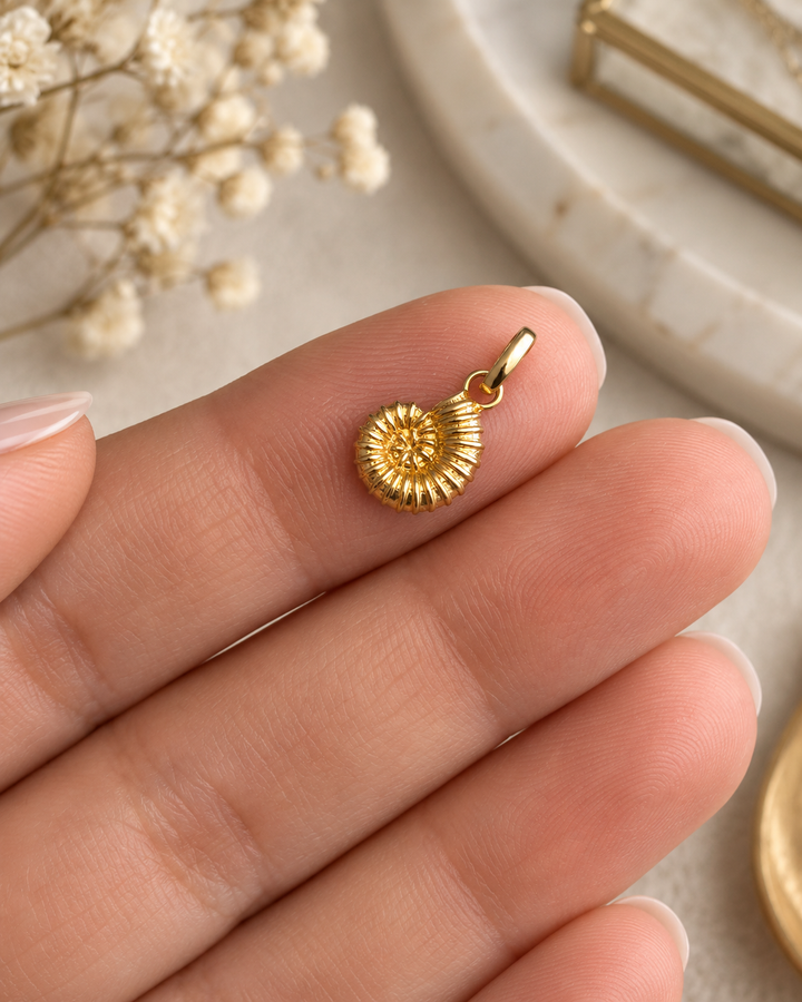 Kleiner Halazoon Anhänger aus 18k Gelbgold in Form eines Schneckenhauses auf der Hand