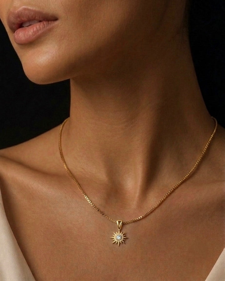 Frau trägt eine filigrane Halskette aus 18 Karat Gelbgold mit einem strahlenden Sonnenanhänger. Der Anhänger ist mit funkelnden weissen Zirkonia besetzt und ruht elegant am Dekolleté. Zeitloser Goldschmuck für Damen, handgefertigt, minimalistisch und vielseitig kombinierbar – ideal für Alltag und besondere Anlässe.