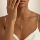 Elegante 18k Gelbgold-Halskette mit spiralförmigem Anhänger, getragen von einer Frau in weissem Kleid. Handgefertigter Goldschmuck mit modernem, minimalistischen Design.