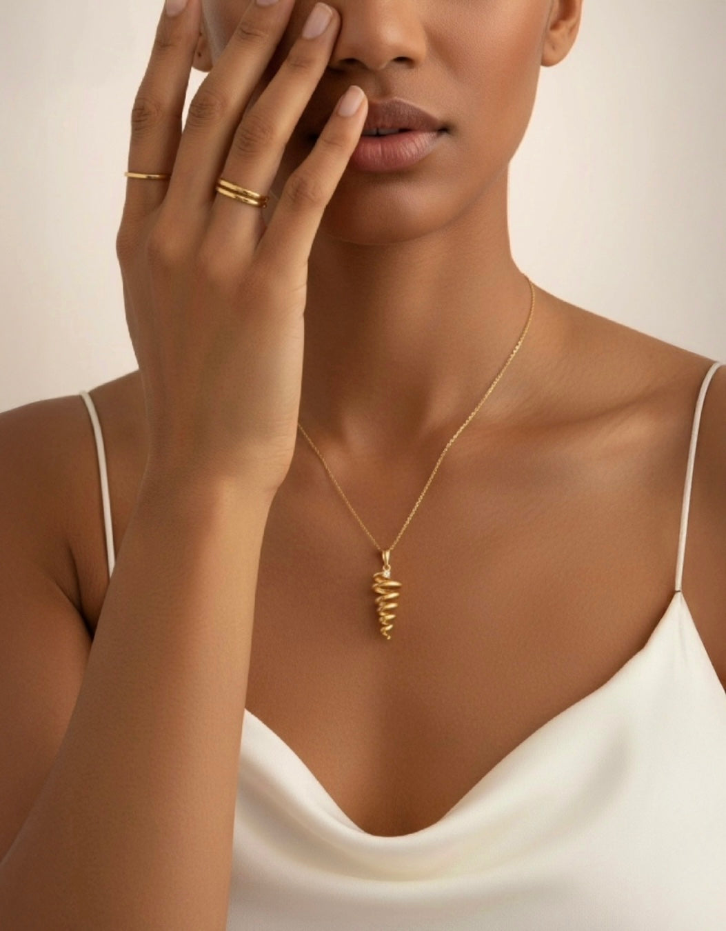 Elegante 18k Gelbgold-Halskette mit spiralförmigem Anhänger, getragen von einer Frau in weissem Kleid. Handgefertigter Goldschmuck mit modernem, minimalistischen Design.