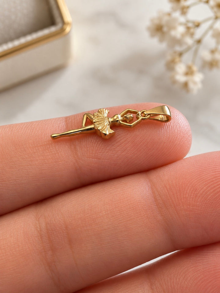 Detailansicht des Raqsandeh Tänzerin-Anhängers aus 18k Gelbgold mit Herzgeste und fein strukturiertem Tutu auf der Hand