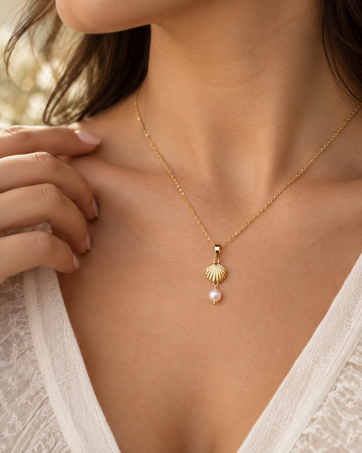 Frau trägt den Sadaf-o Morvarid Muschel-Anhänger aus 18k Gelbgold mit zarter Zuchtperle an einer feinen Goldkette