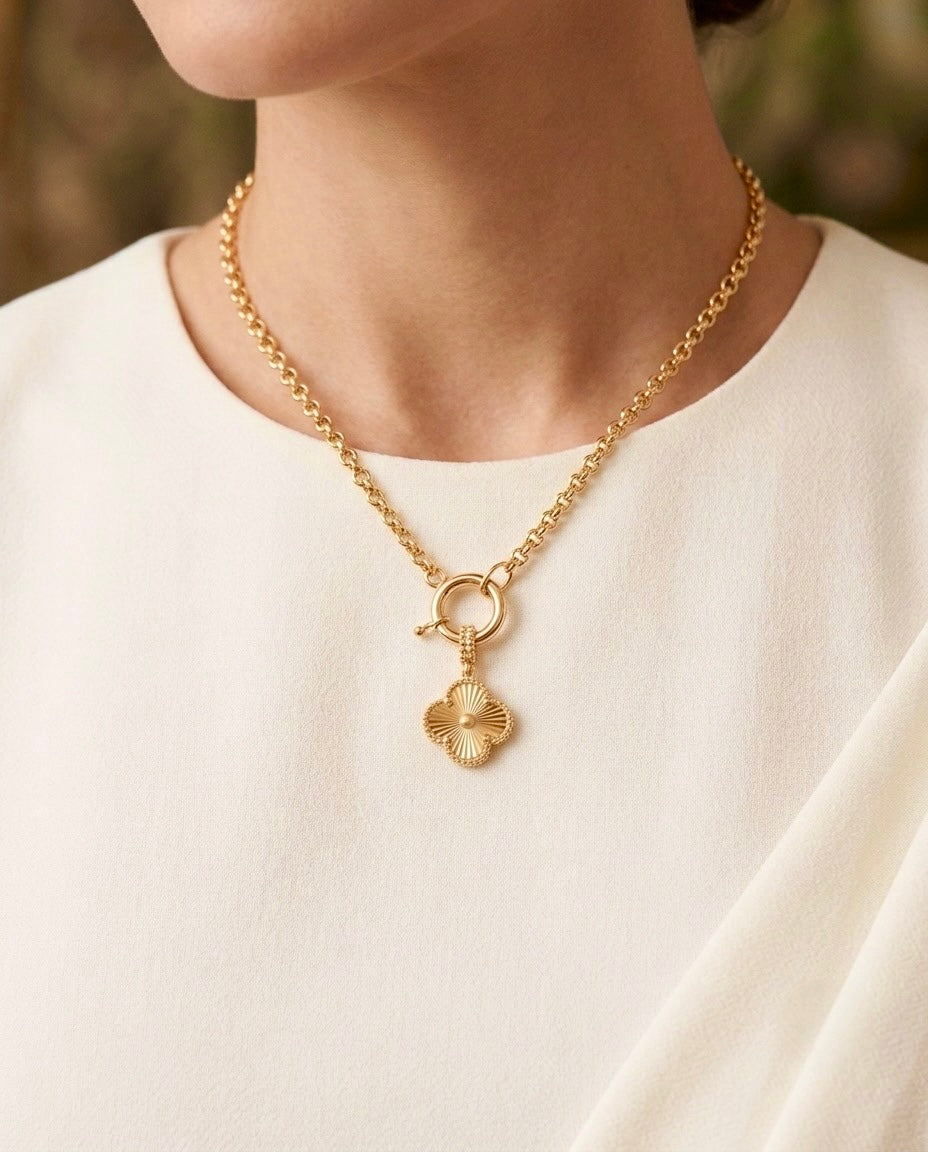 18 Karat Gelbgold-Halskette mit dekorativem Ringverschluss und filigranem Kleeblatt-Anhänger, elegant getragen zu einer weissen Bluse. Zeitloses Schmuckstück aus echtem Gold mit feiner Struktur und luxuriöser Ausstrahlung – handgefertigt für stilbewusste Frauen.