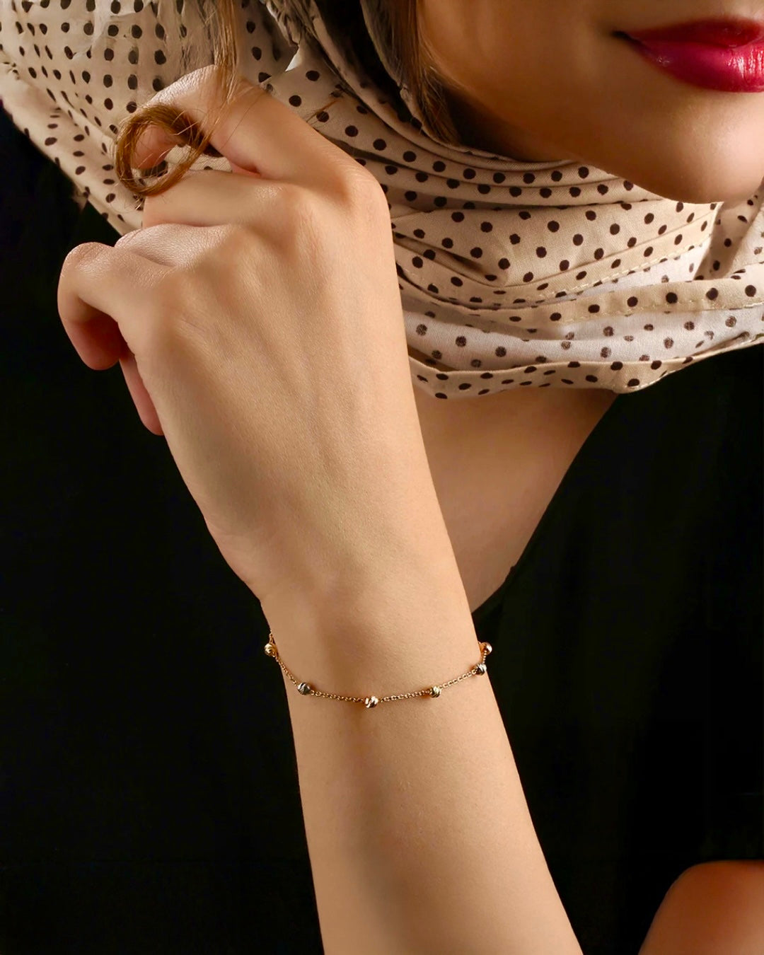 Nahaufnahme einer Frau mit elegantem 18k Goldarmband – feine Gliederkette mit kleinen Kugeln in Gelb-, Weiss- und Roségold, getragen am Handgelenk; dezentes, luxuriöses Design, ideal für stilvolle Auftritte.