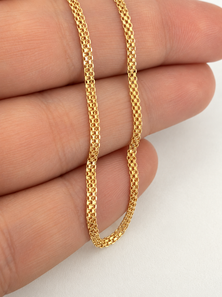 Nahaufnahme des Zanjir-e Bizmark Zarif Armbands aus 18K Gelbgold mit fein ineinandergreifenden Bismarck-Kettengliedern auf den Fingern.