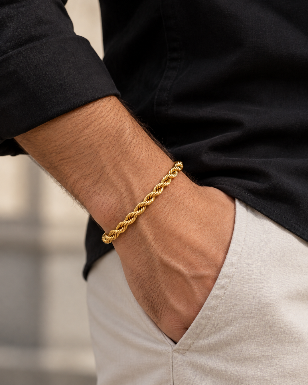 Ringzopf-Armband aus 18k Gelbgold getragen von einem Mann mit Hand in der Hosentasche