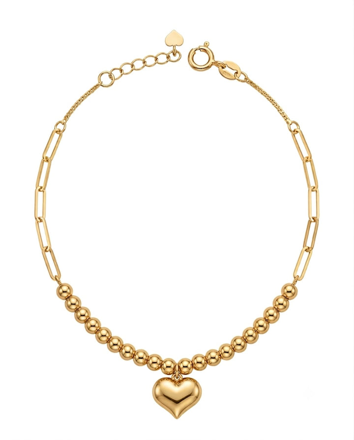 18k Gelbgold-Armband mit Herz, feiner Ankerkette, Paperclip-Elementen und Goldkugeln, freigestellt auf hellem Hintergrund.