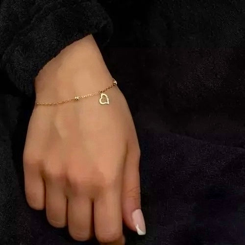 Elegantes Armband aus 18k Gelbgold mit filigraner Kette und Herz-Anhänger, getragen am Handgelenk