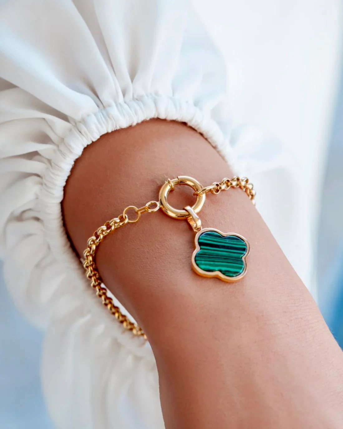 Elegantes 18k Gelbgold-Armband mit feiner Gliederkette, rundem Federring-Verschluss und Kleeblatt-Anhänger aus grünem Malachit, getragen am Handgelenk; luxuriöser, zeitloser Goldschmuck mit natürlicher Steinstruktur.