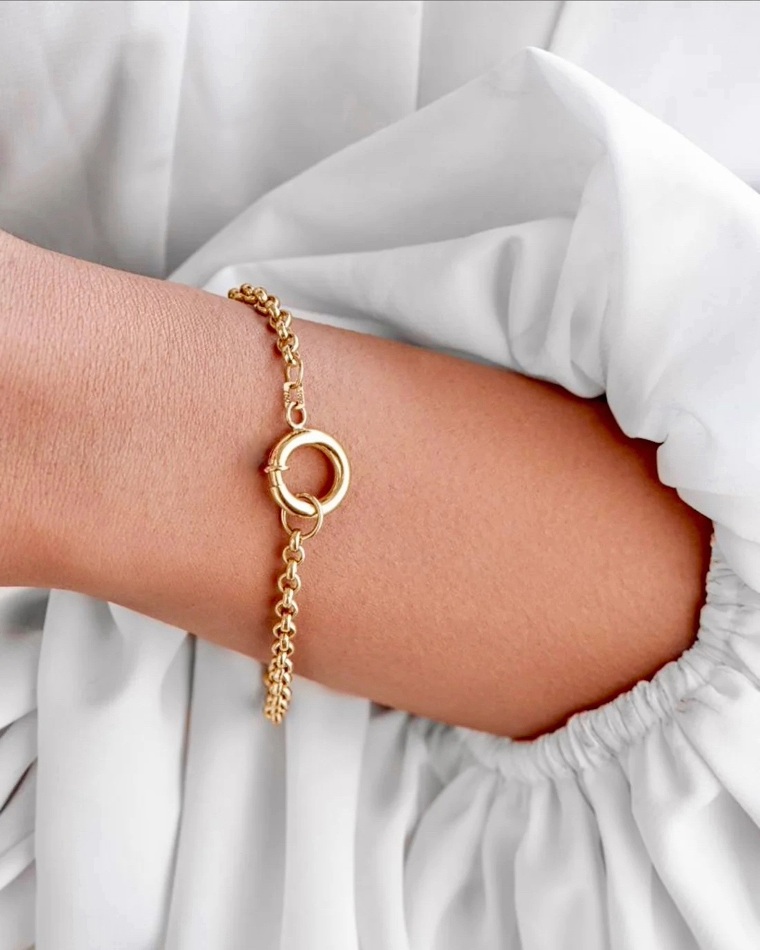 Elegantes 18k Gelbgold-Armband mit feiner Gliederkette und rundem Federring-Verschluss, am Handgelenk getragen; minimalistischer, zeitloser Goldschmuck mit hochglanzpolierter Oberfläche.