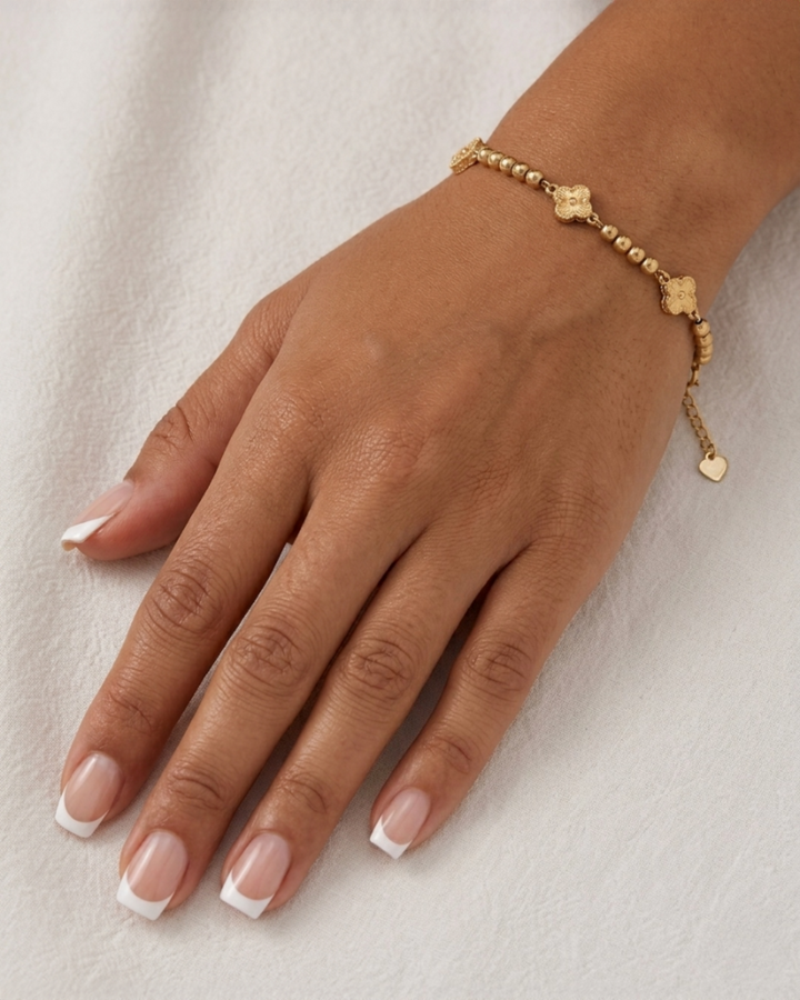 Detailaufnahme eines 18k Goldarmbands mit Goldkugeln und fünf Blütenmotiven