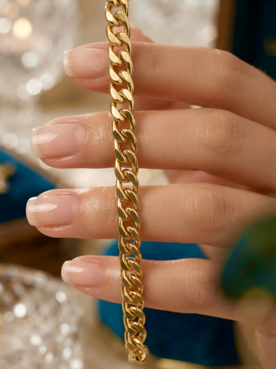 Nahaufnahme einer goldenen Panzerkette aus 18 Karat Gelbgold, die zwischen den Fingern einer Hand gehalten wird. Die polierten, ineinandergreifenden Kettenglieder glänzen vor einem weich verschwommenen Hintergrund.