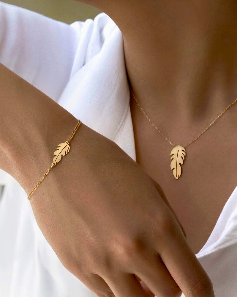 Armband aus 18k Gelbgold mit filigranem Anhänger in Form einer stilisierten Feder – Par-e Asal (Honigfeder). Zeitloses Design auf feiner Doppelankerkette, elegant am Handgelenk getragen.