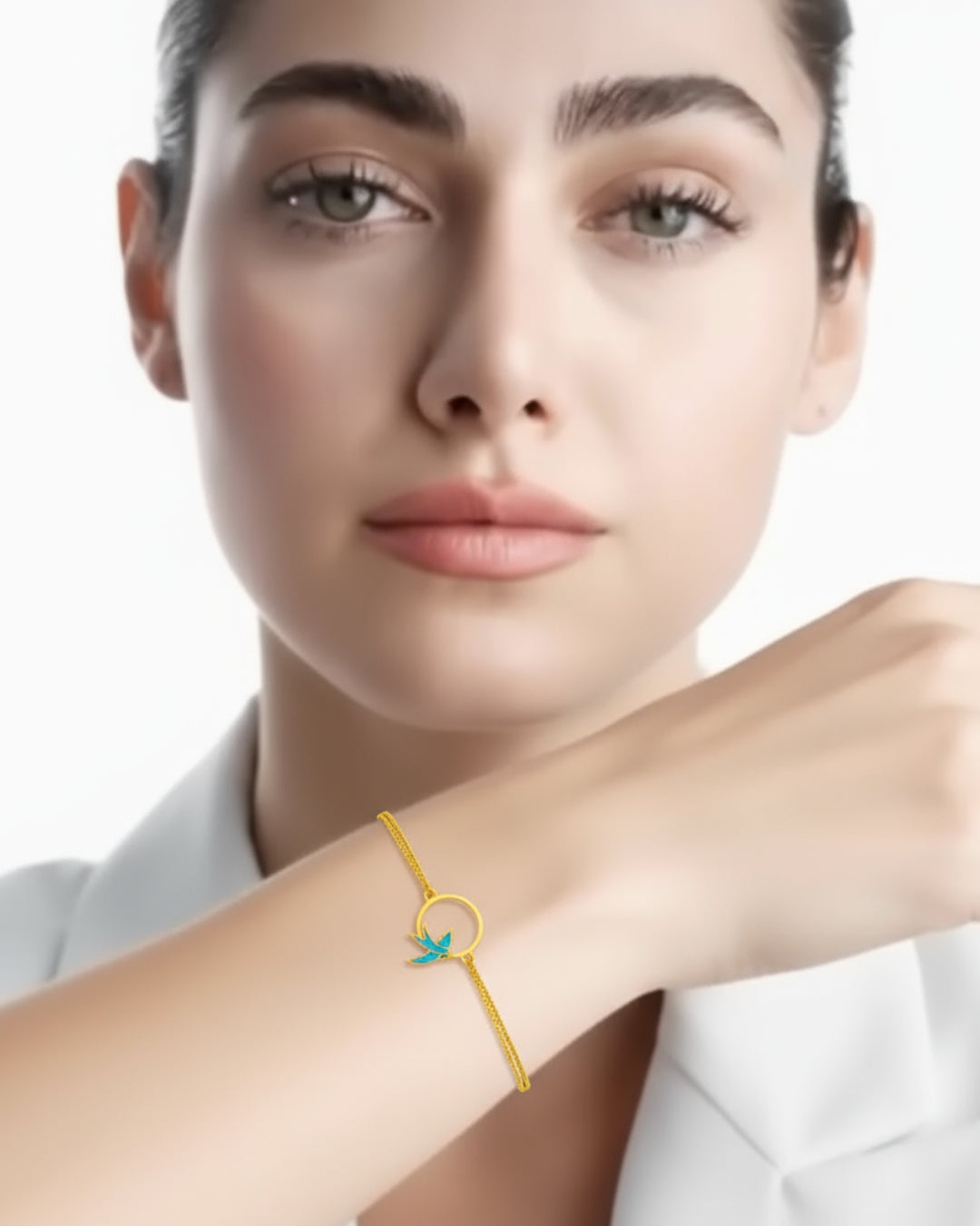 Armband aus 18k Gelbgold mit emaillierter Schwalbe im Kreis – getragen von einem Model mit weissem Blazer, elegant & handgefertigt.