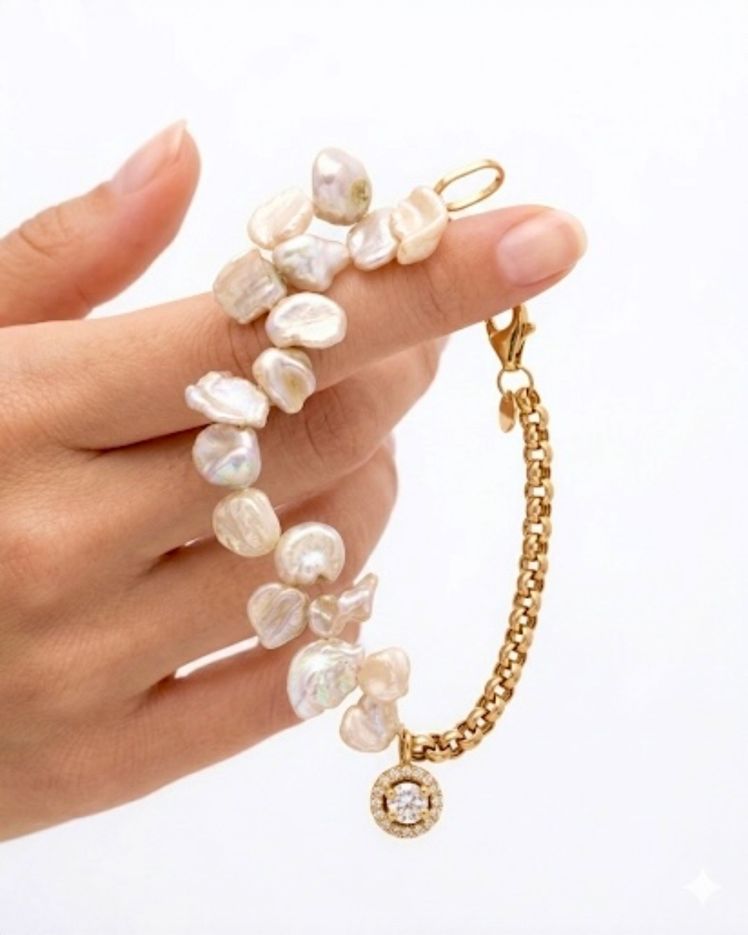 Detailaufnahme eines Armbands mit unregelmässigen Barockzuchtperlen, Goldkette und funkelndem Zirkonia-Anhänger 💛