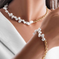 Model trägt eine Halskette und ein Armband aus 18 Karat Gelbgold mit echten weissen Barock-Süsswasserperlen. Handgefertigter Luxusschmuck, der die natürliche Schönheit unregelmässiger Perlen mit der zeitlosen Eleganz von Gold vereint. Ideal für stilbewusste Frauen, die einzigartigen Schmuck mit Charakter schätzen.