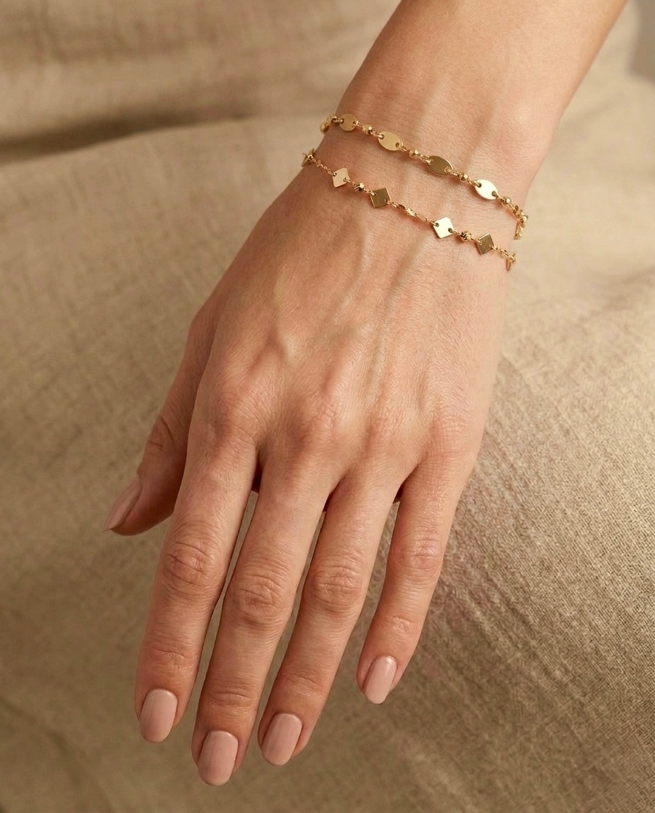 18 Karat Gelbgold-Armbänder mit geometrischen Plättchen und feiner Kugelkette am Handgelenk einer Frau – filigraner, eleganter Goldschmuck für den Alltag und zum Layering von Ziba Gold.