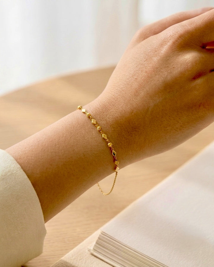 Elegantes 18 Karat Goldarmband mit filigranen geometrischen Elementen am Handgelenk getragen. Das feine Design verleiht dem Schmuckstück eine zeitlose und feminine Ausstrahlung und eignet sich ideal für den Alltag sowie besondere Anlässe.
