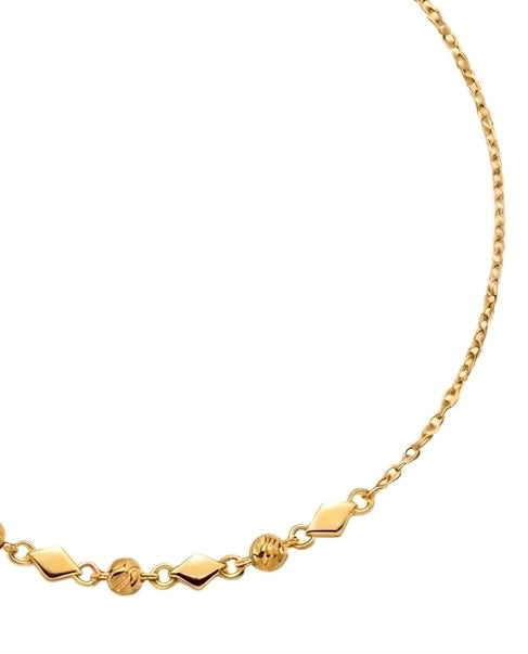 Detailaufnahme der geometrischen Goldglieder und polierten Kugeln eines feinen Gelbgoldarmbands