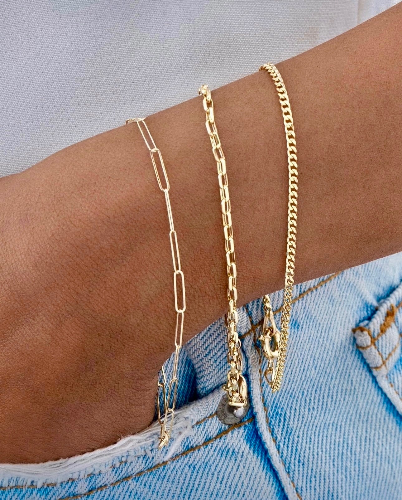 Armband Gelbgold 18k – Reshteh (Verbindung), filigranes Kettendesign mit länglichen, rechteckigen Gliedern, getragen am Handgelenk, kombiniert mit weiteren feinen Goldarmbändern.